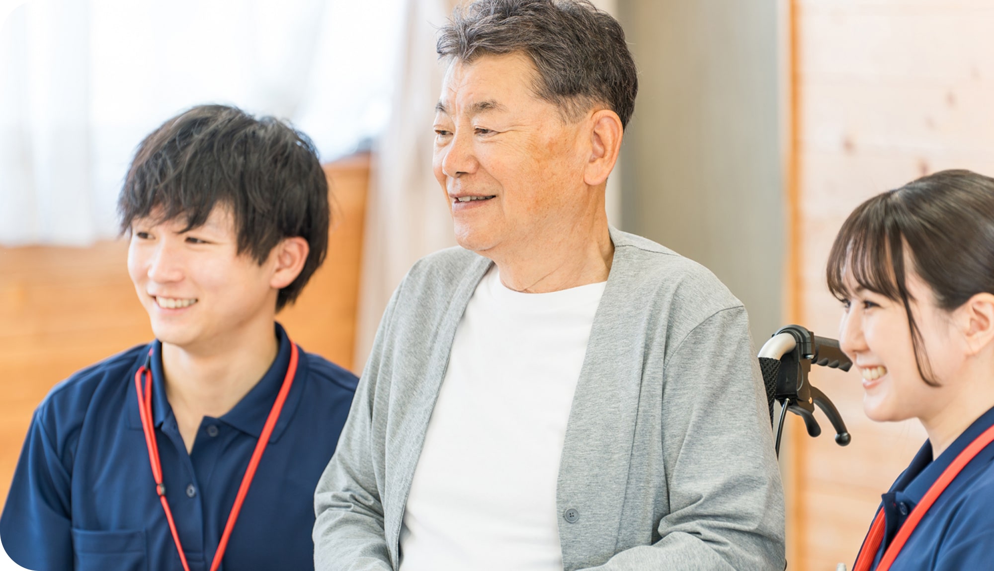 車いすに乗っている男性と両隣に笑顔の男女がかがんでいる